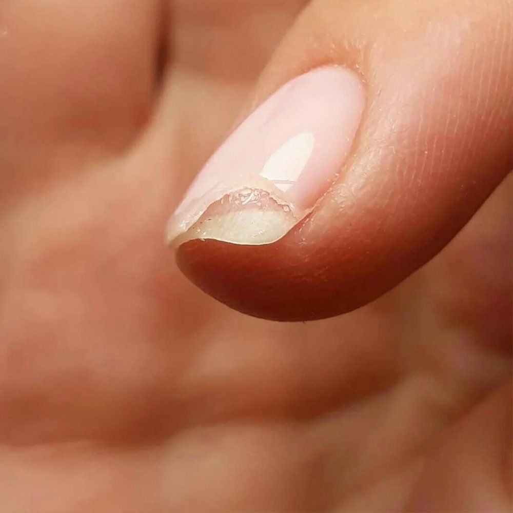 Close-up of a natural nail edge protected by a grown-out layer of hard gel.