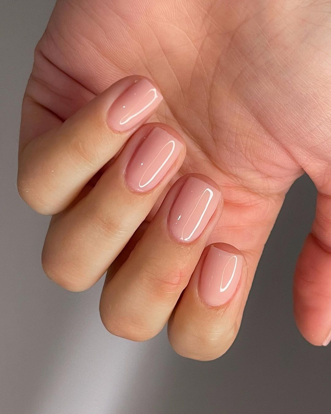 Glossy blush-pink hard gel overlay on natural squoval nails catching the light.